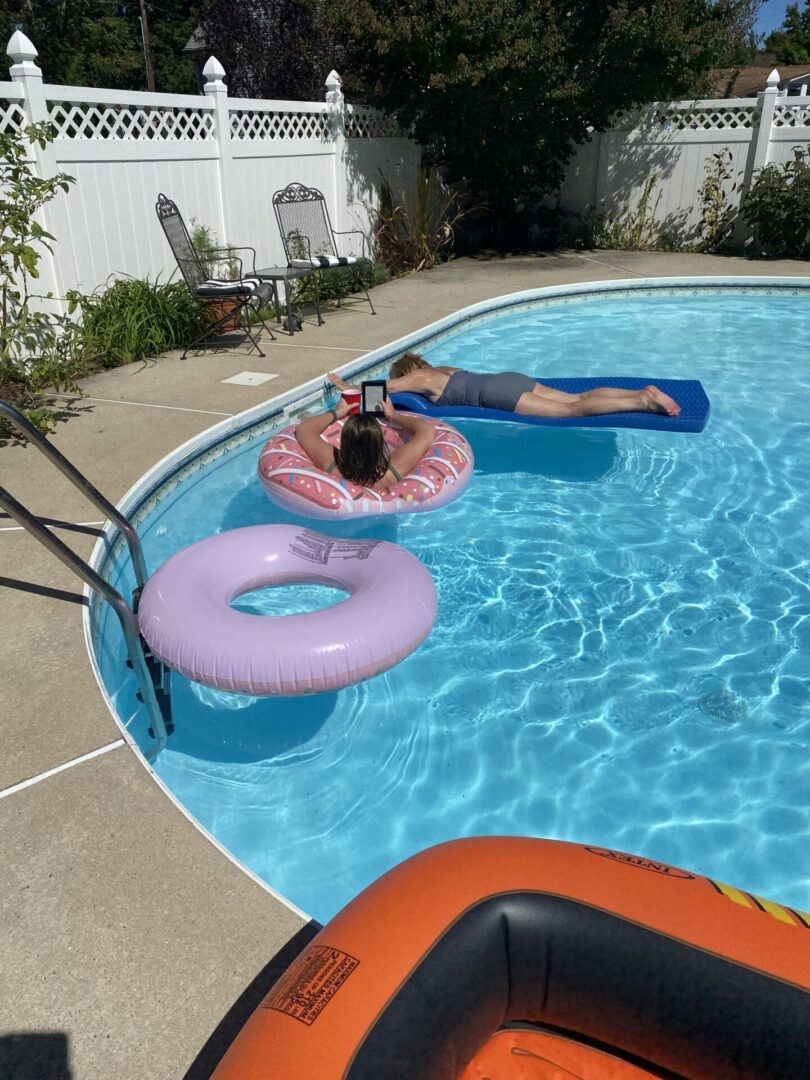 Person relaxing in a pool on a pink inflatable ring.