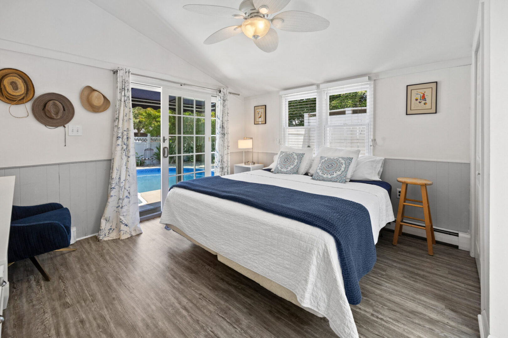 Bright, cozy bedroom with white and blue bedding and sliding glass doors to the outdoors.