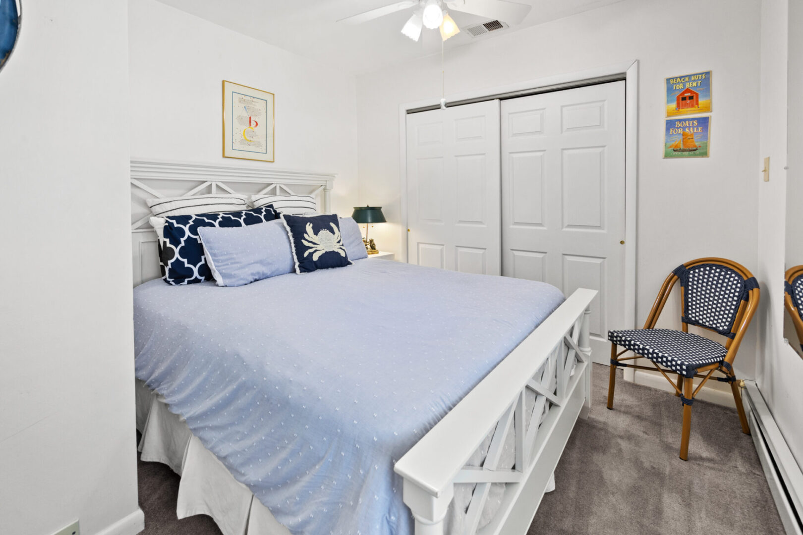 Bright bedroom with a cozy blue bed and white furniture.