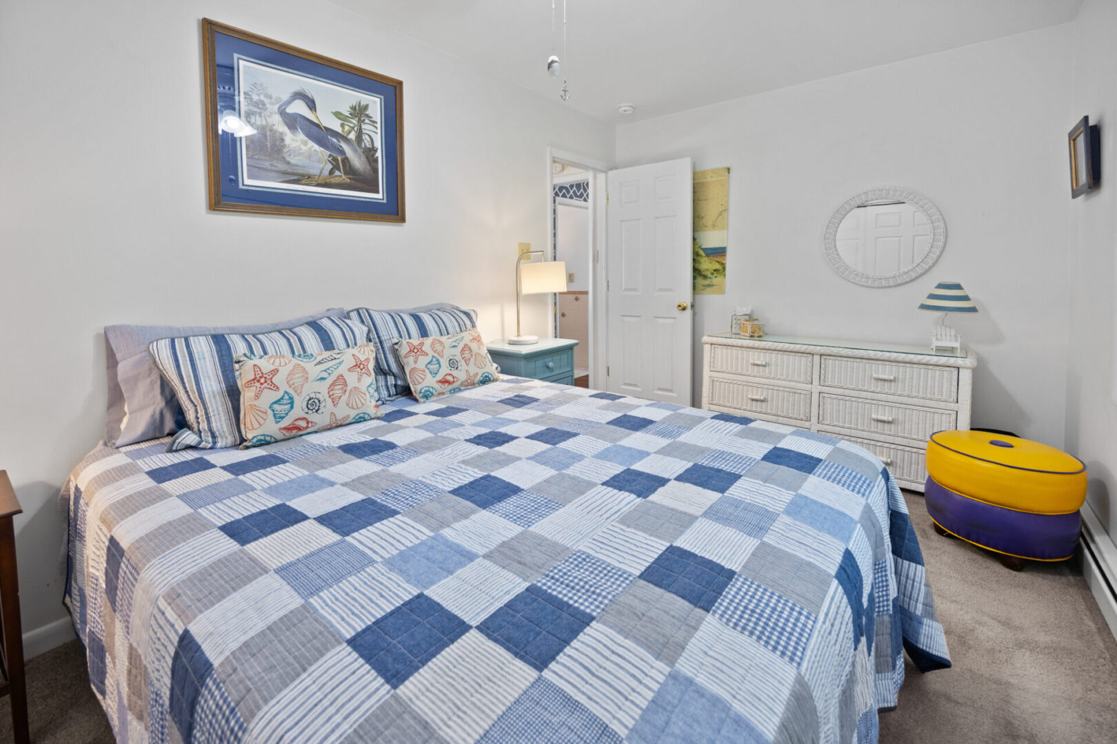 Cozy bedroom with a blue patchwork quilt and nautical-themed decor.