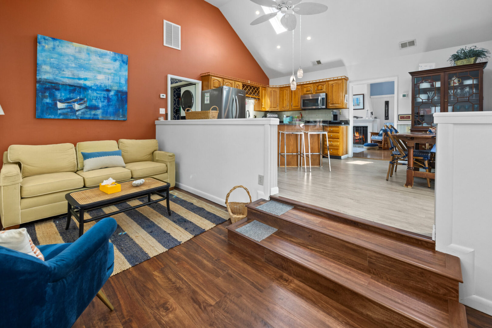 Bright living room with wooden floors, beige sofa, and open kitchen.