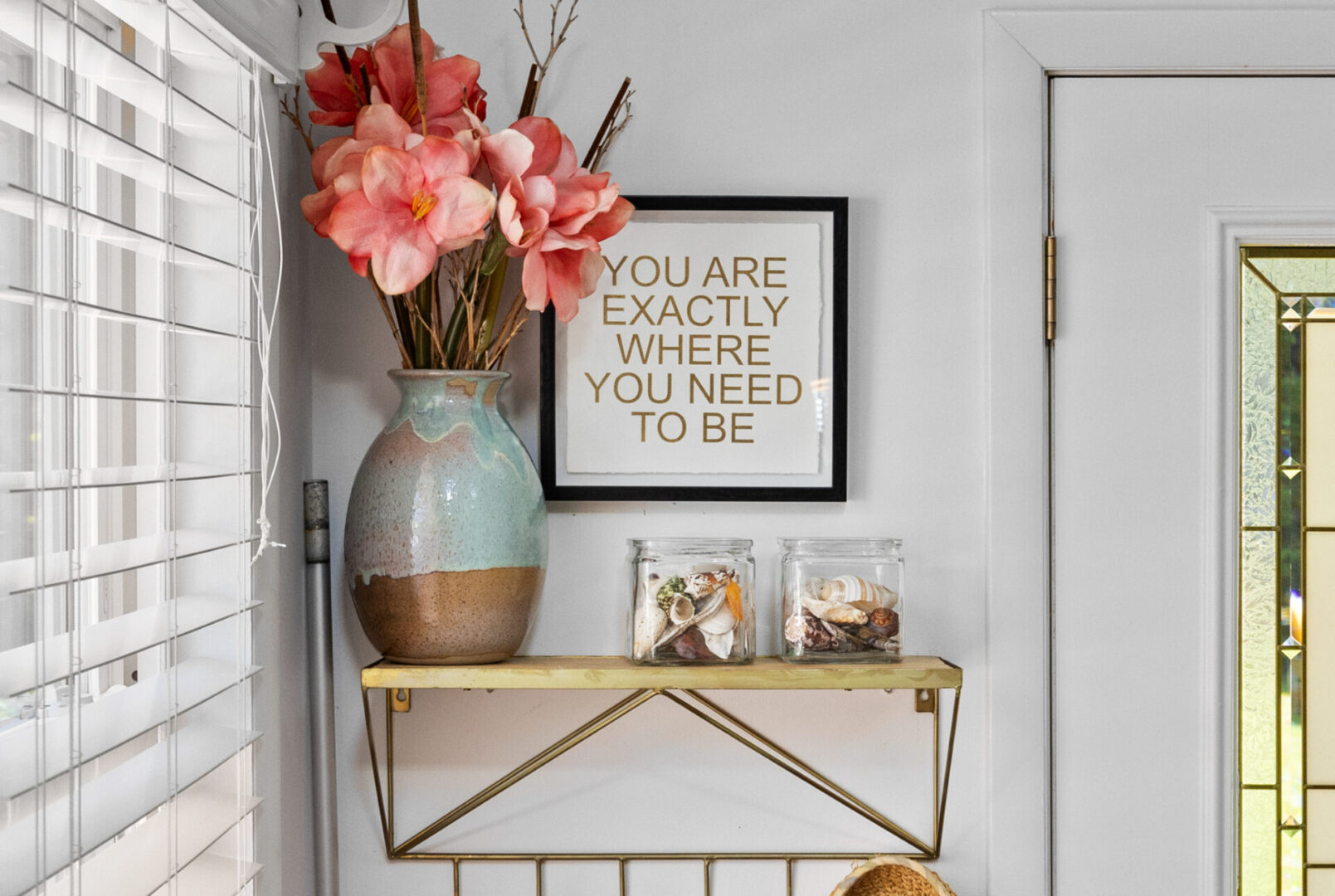 A decorative shelf with flowers and a motivational sign.