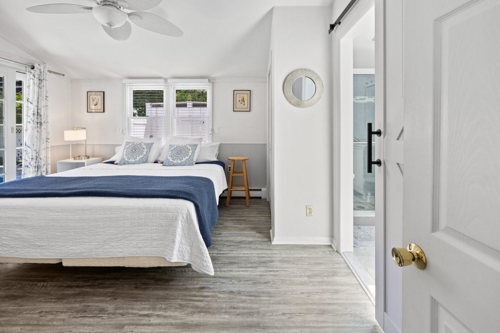 Bright bedroom with blue and white bedding and wooden flooring.