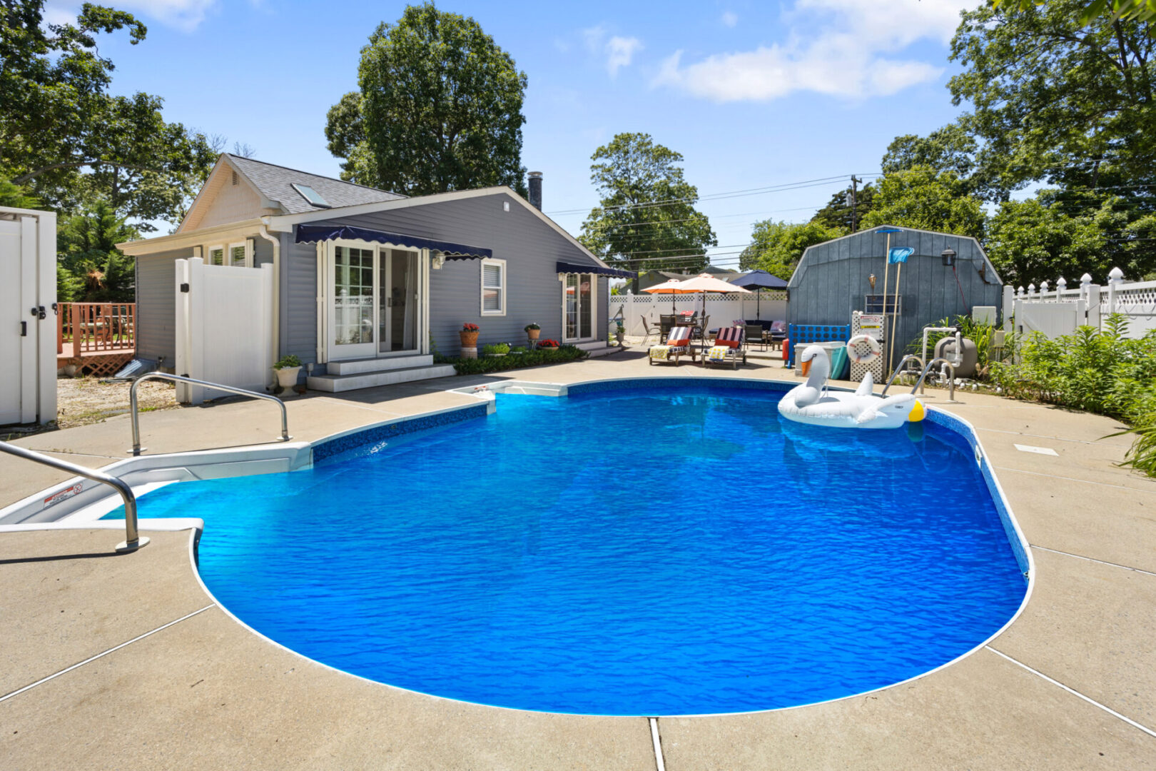 Inviting backyard pool with lounge chairs and umbrella on a sunny day.